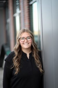 Portrait of Bayleigh, a receptionist, smiling indoors, appears to be a professional staff headshot.